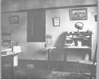 SA0493 - Photo of a room interior, showing a desk and chair. Identified on the back.